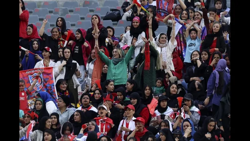 Cầu thủ Iran với áo đỏ và mũ đỏ đang cố gắng đối phó với cầu thủ Tanzania trong trận đấu.